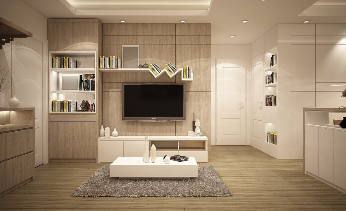 A modern living room featuring white furniture and a flat-screen television on the wall